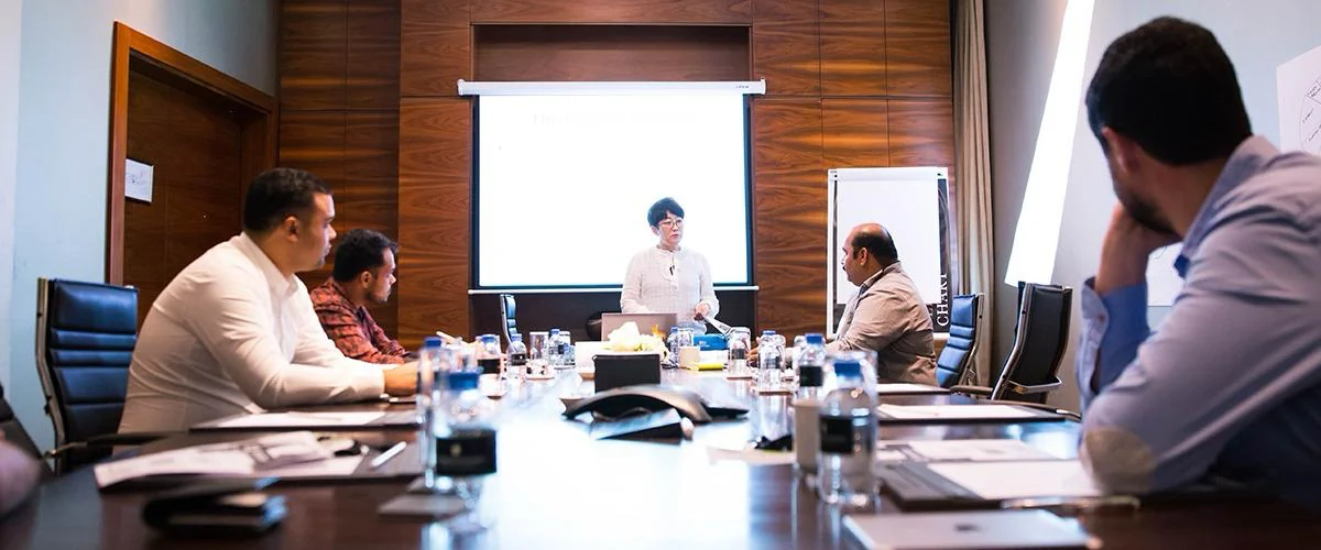 A facilitator speaking with a team around a meeting table